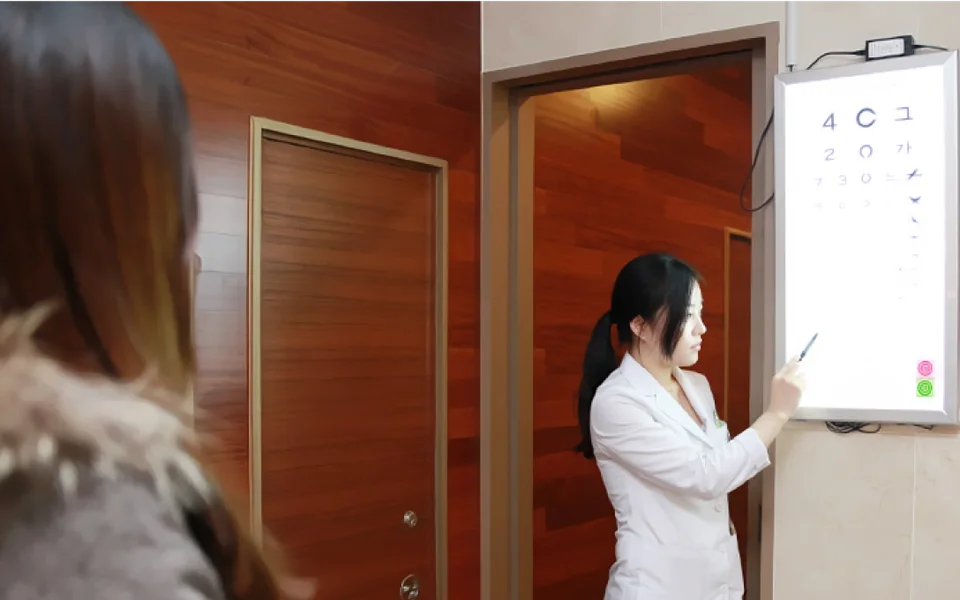 시력표로 시력과 주로 쓰는 눈을 확인하는 검사 장면